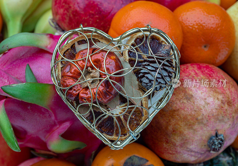 Golden heart shaped mesh case is filled with Dried fruits on Variety of assorted fruits.